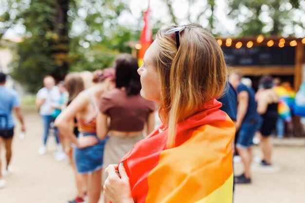 Young woman with LGBTQI pride rainbow flag on the street in the park Pride Month concept