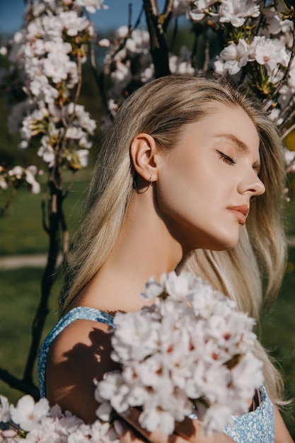 Young woman with long blonde hair outdoors in a park enjoying sunny weather