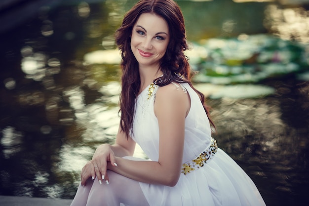 Young woman with long hair and pretty face in white dress posing