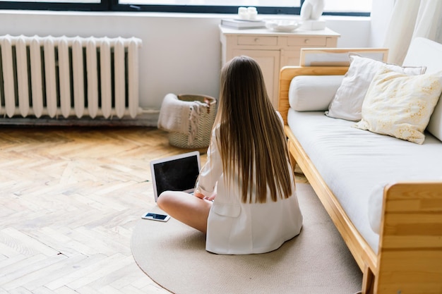 Young woman with long legs and long hair posing on the sofa in a cozy apartment in the morning