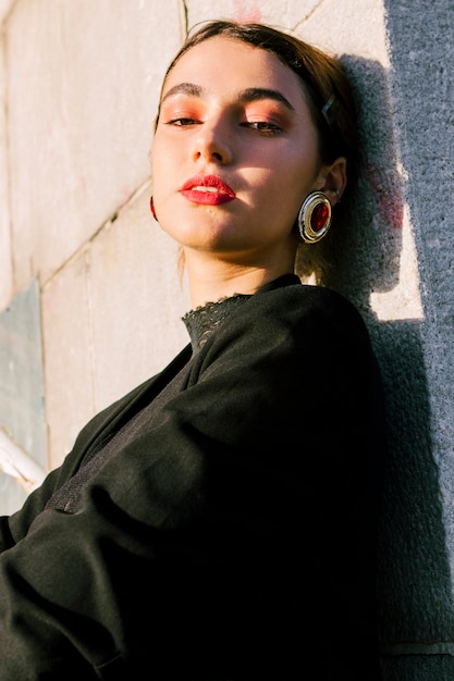 Young woman with make-up wearing red earrings looking at camera