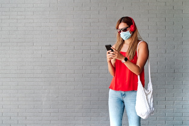 Young woman with a mask using her mobile