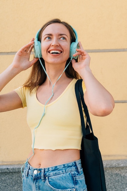 Young woman with mint headphones and black cap outside on the street