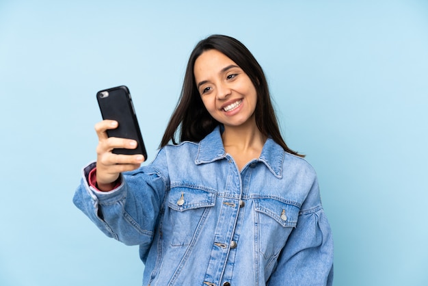 Young woman with a mobile over isolated wall