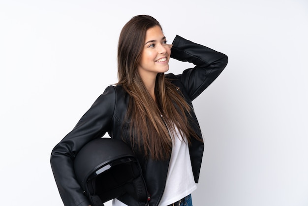 Young woman with a motorcycle helmet over isolated white wall laughing