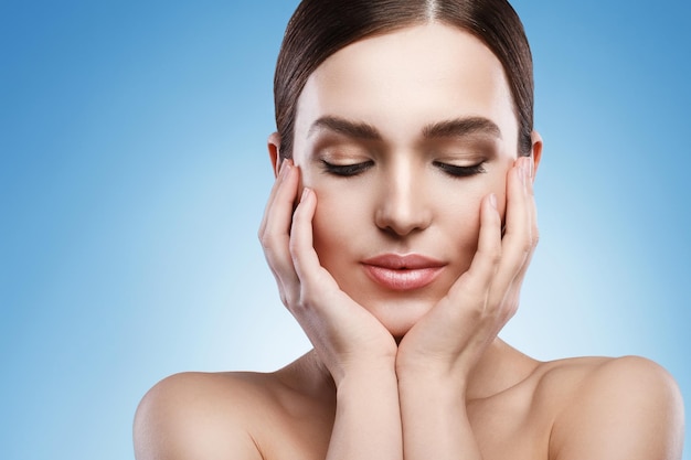 Young woman with natural makeup and smooth skin against light blue background