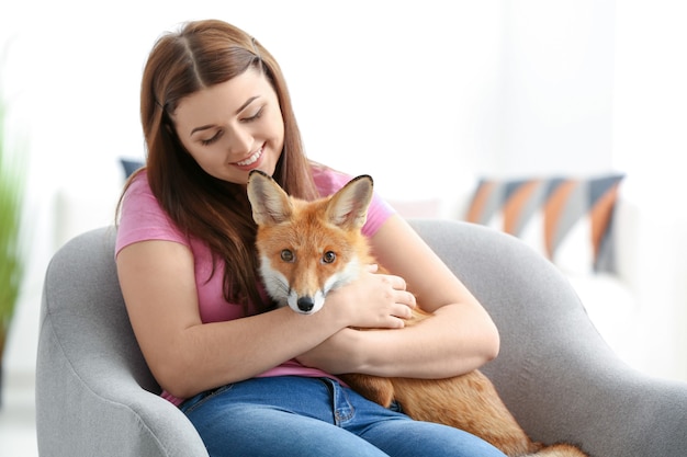 Young woman with pet fox indoors