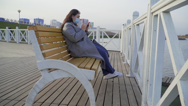 Photo a young woman with a phone in her hands wearing a mask