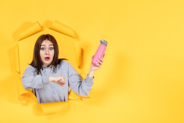 young woman with pink bottle on a yellow paper background gym athlete fit indoor