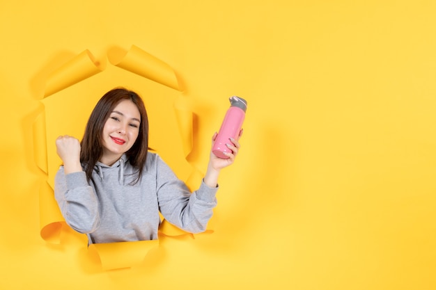 young woman with pink bottle on the yellow paper background gym athlete fit indoor