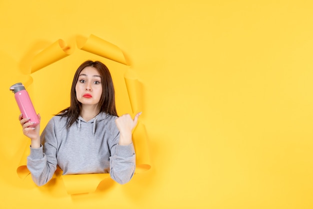 young woman with pink bottle on yellow paper background gym fit athlete indoor