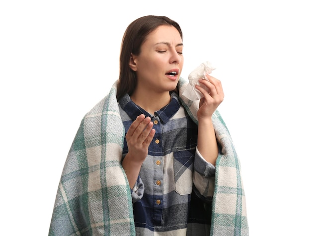 Young woman with plaid suffering from runny nose on white background