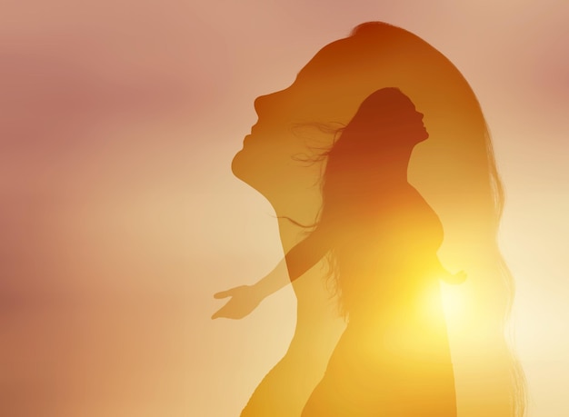 Young woman with raising hands on the sunset sky background.