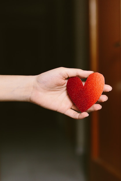 Young woman with red glitter heart shaped cardboard on the hand. Girl holding a cardboard heart for st. valentine's day. Love and Valentines concept.