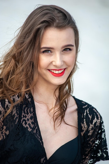 A young woman with a red lipstick smiles at the camera.