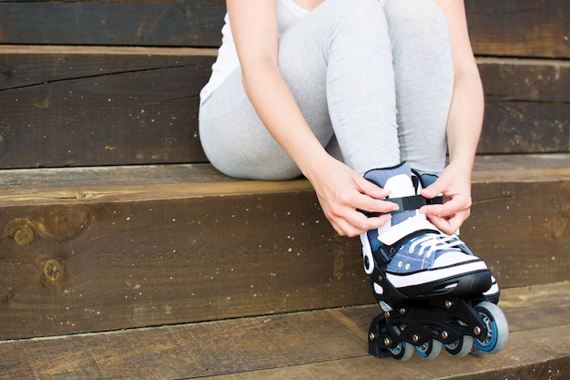 young woman with roller-skates sitting on a staircase