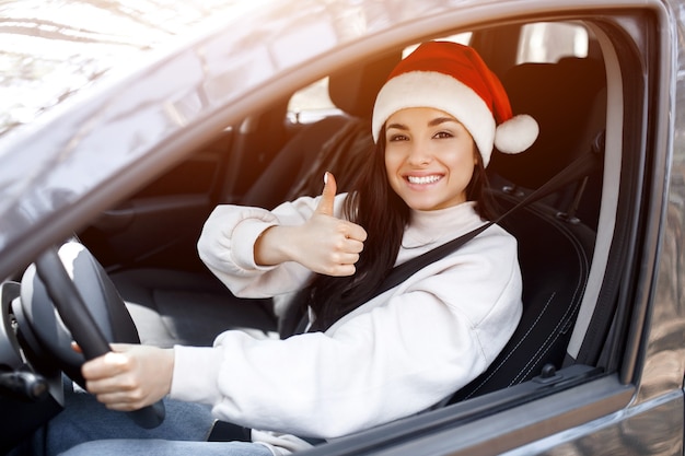 Young woman with Santa's hat driving her car