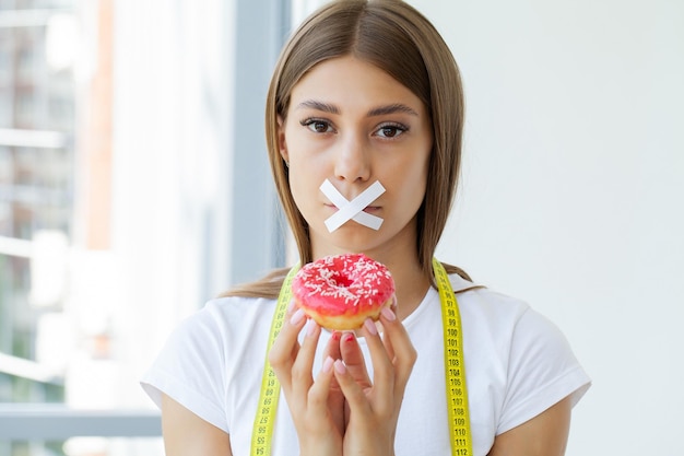 Young woman with sealed mouth giving up junk food