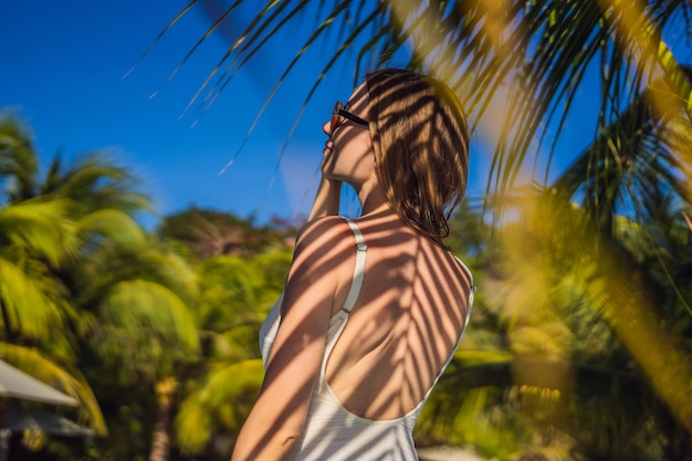 Young woman with the shadow of the palm leaf on her back Relaxing on the seaside