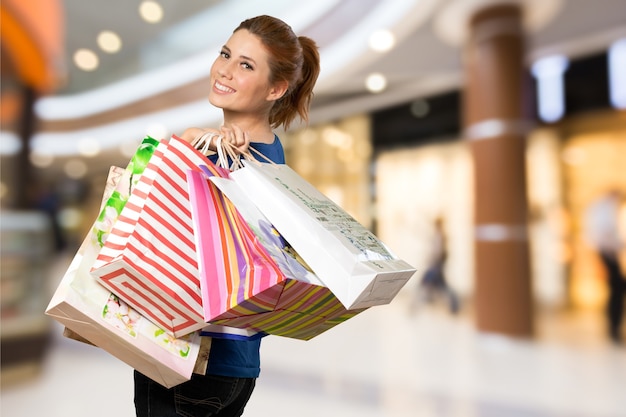 Young woman with shopping bag on blurred shopping mall background