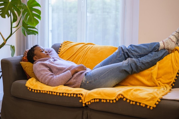 Young woman with short curly hair napping on the sofa in her living room Concept rest nap sleep