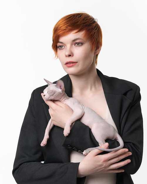 Young woman with short hair holding in hands sleeping Sphynx Hairless Cat blue mink and white color