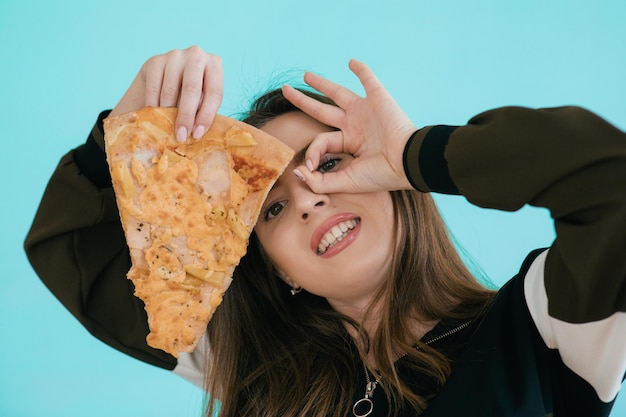 Young woman with slice of delicious pizza on color background