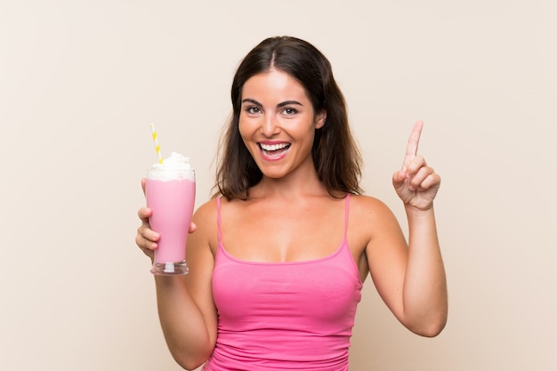 Young woman with strawberry milkshake pointing up a great idea