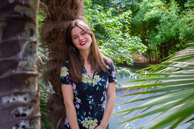 Young woman with stylish clothes posing in a paradisiacal park at sunset