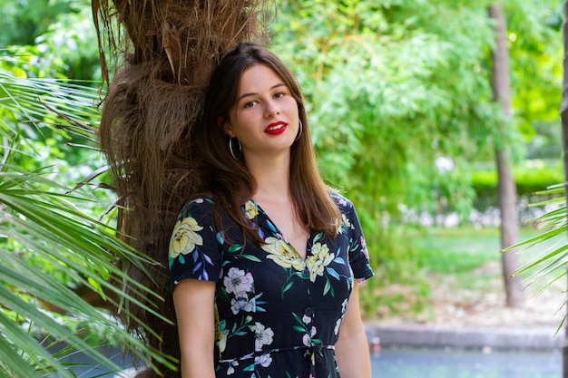 Young woman with stylish clothes posing in a paradisiacal park at sunset