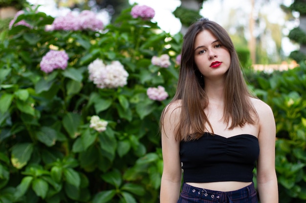 Young woman with stylish clothes posing in a paradisiacal park