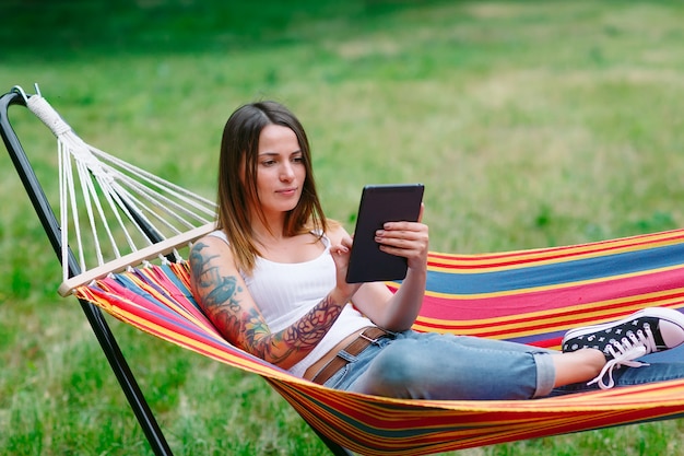 Young woman with tablet on the hammock