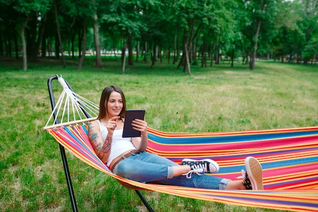 Young woman with tablet on the hammock