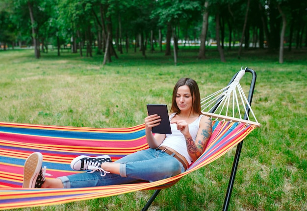 Young woman with tablet on the hammock