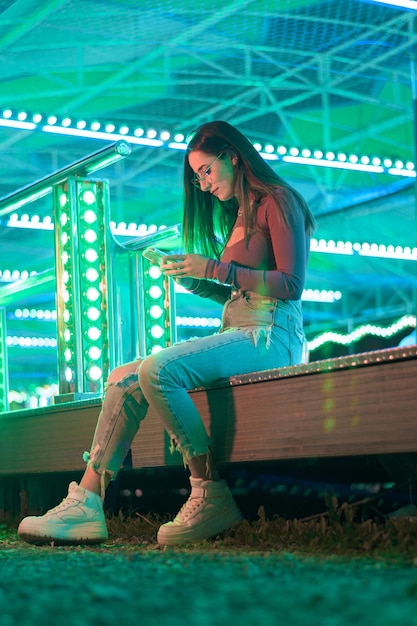 Young woman with a telephone illuminated by fairground lights