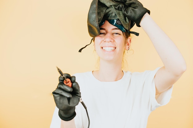 Young woman with a welder mask gloves and welding tools smiling to camera with happy attitudeNew job opportunities for young women conceptCopy Studio shot Woman new income ways evolution of job