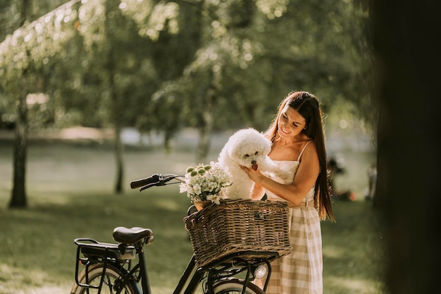 Young woman with white bichon frise dog in the basket of electric bike