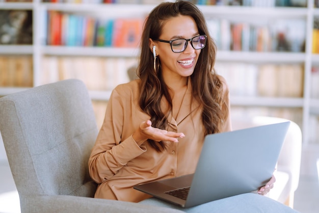 Young woman with wireless headphones calling on laptop Online conference Freelancer concept