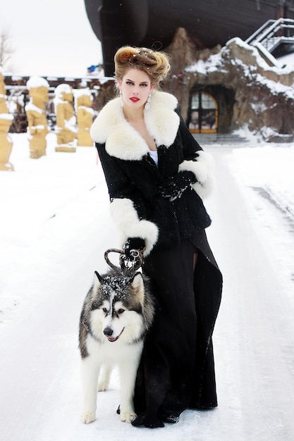 Young woman with wolf dog in snow