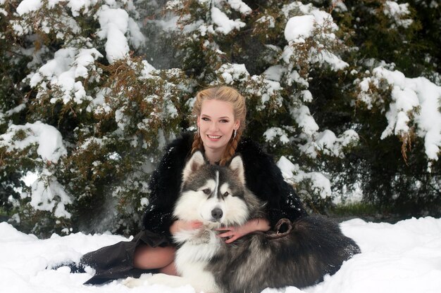 Young woman with wolf dog in snow