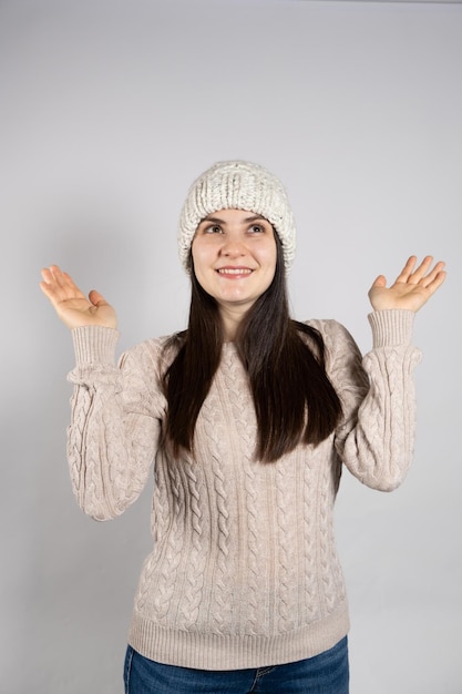 A young woman in a wool hat and sweater looks up and smiles