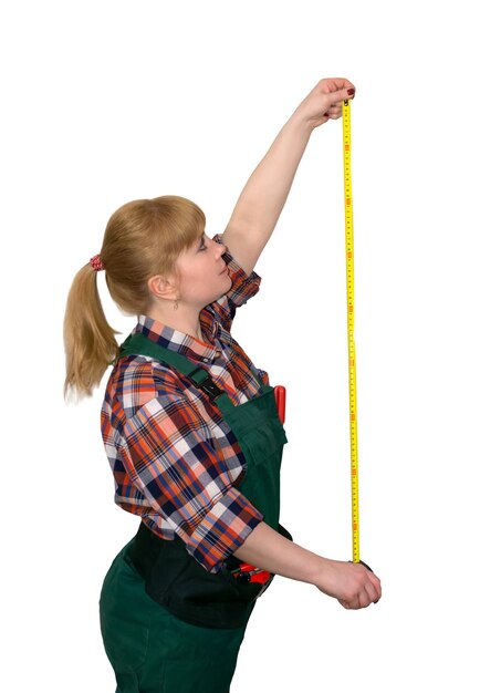 Photo young woman in work overalls holding a tensioned tape measure isolated on white background