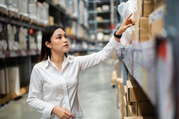 Young woman worker checking inventory in the warehouse store