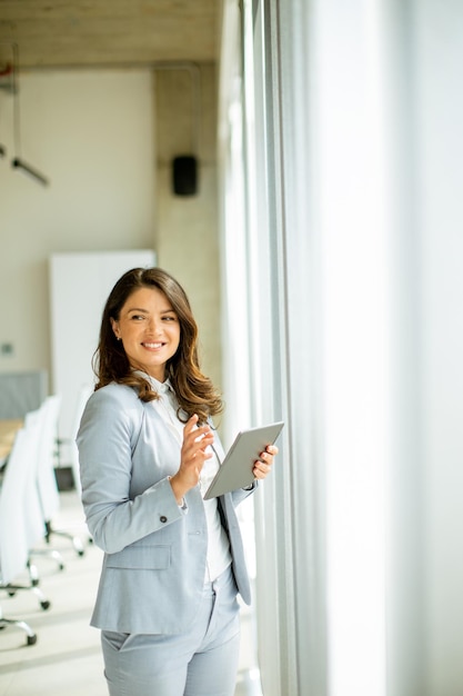 Young woman working on digital tablet by the office window