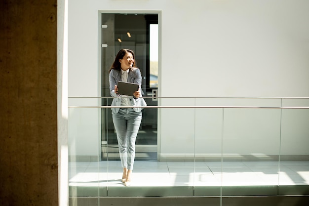 Young woman working on digital tablet in the office hallway