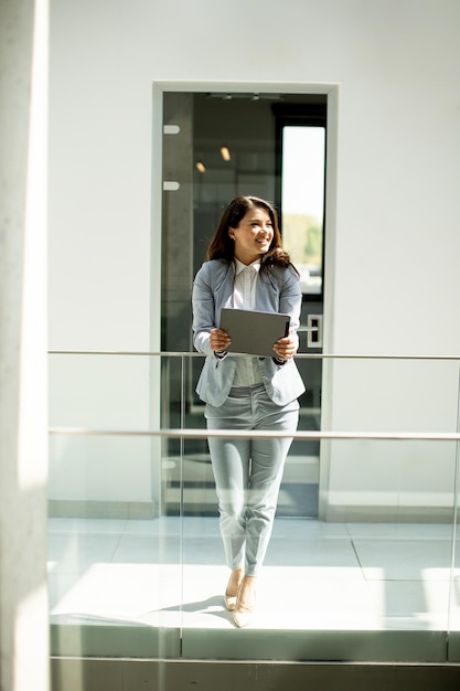 Young woman working on digital tablet in the office hallway