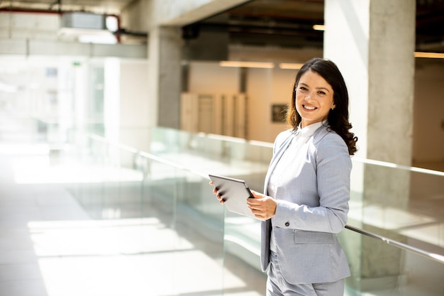 Young woman working on digital tablet in the office hallway