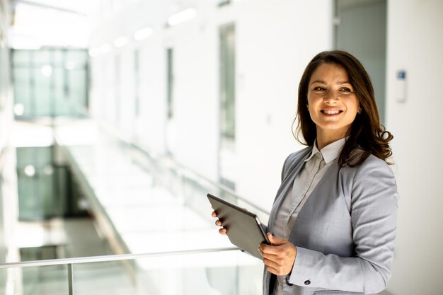 Young woman working on digital tablet in the office hallway