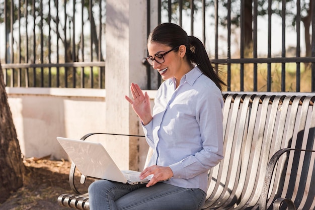 Young woman working on her computer outdoors on a sunny afternoon sitting on a bench in the park