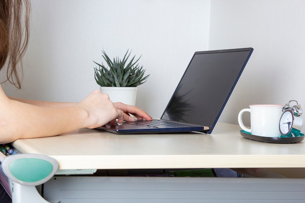 Young woman working for laptop from home on desk.